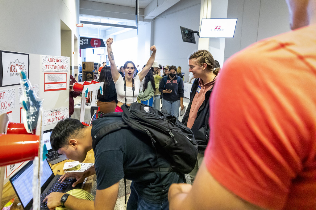 A woman celebrates while another one signs a sheet.