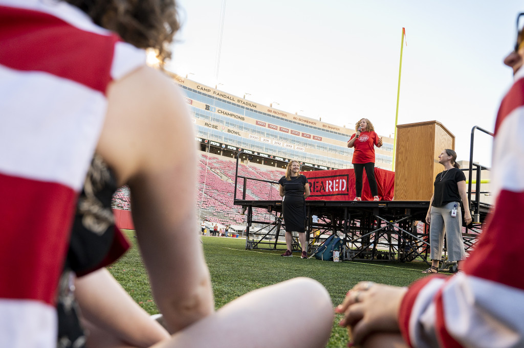 A woman talks on stage - a student is visible sitting in the foreground, and listening.