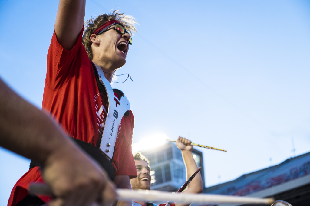 A drummer holds his arm in the air, smiling.