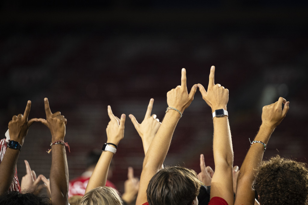 A shot of arms raised overhead against the night sky, making W signs.