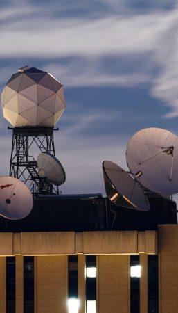 Modern weather sensing equipment, including antennae and satellites, sit atop a research building on the UW–Madison campus.