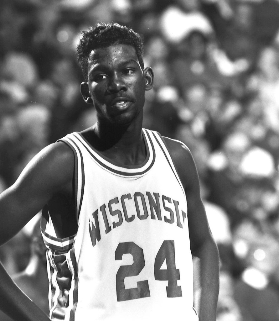 A man in a No. 24 Wisconsin jersey stands with his hands on his hips.