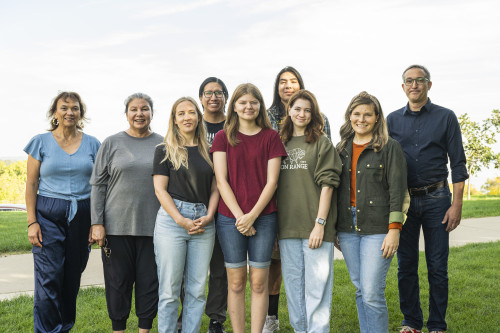 The nine tour guides stand outside on Observatory Hill. They're standing in two rows and smiling to the camera.