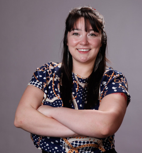 In this portrait photo, Samantha Macksey stands with her arms crossed and smiles to the camera.