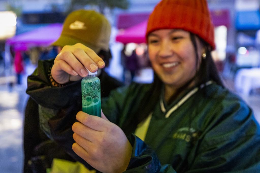 A woman smiles as she holds a lava lamp.