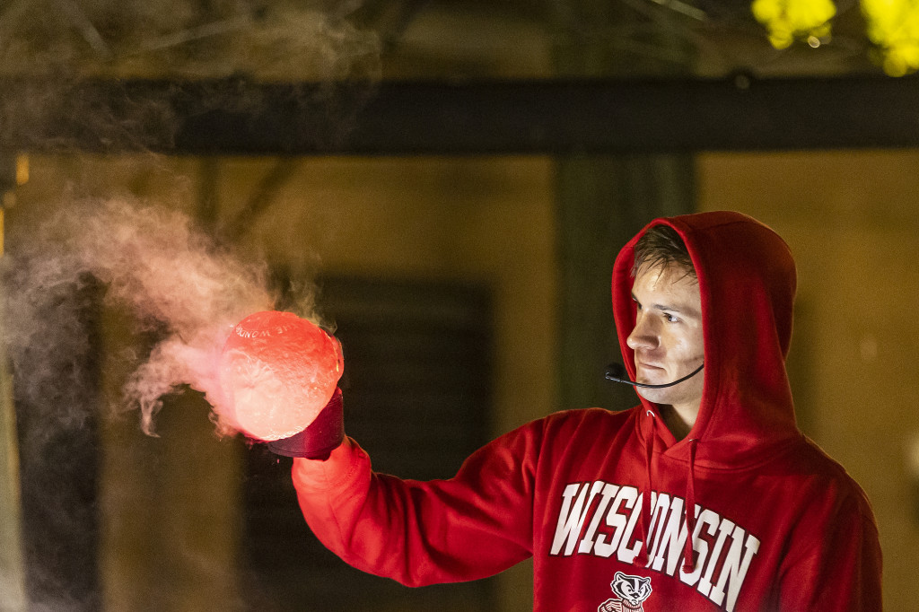 A man in a red Wisconsin sweatshirt holds up a filled balloon.