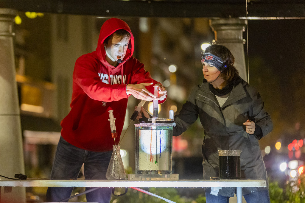 A person mixes paint in a bucket.