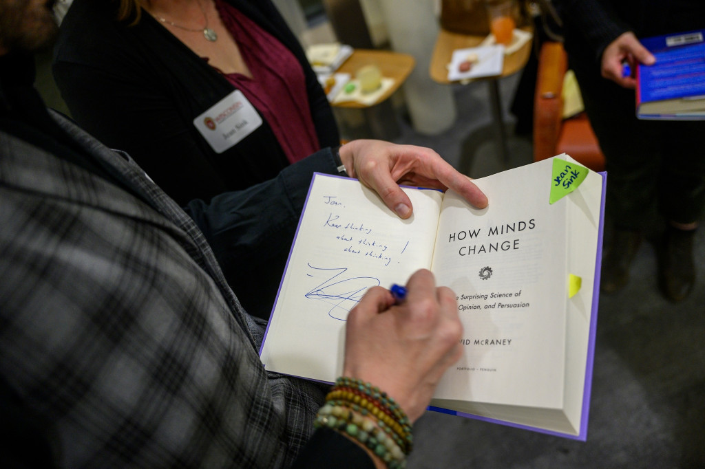 A hand is pictured signing a book.