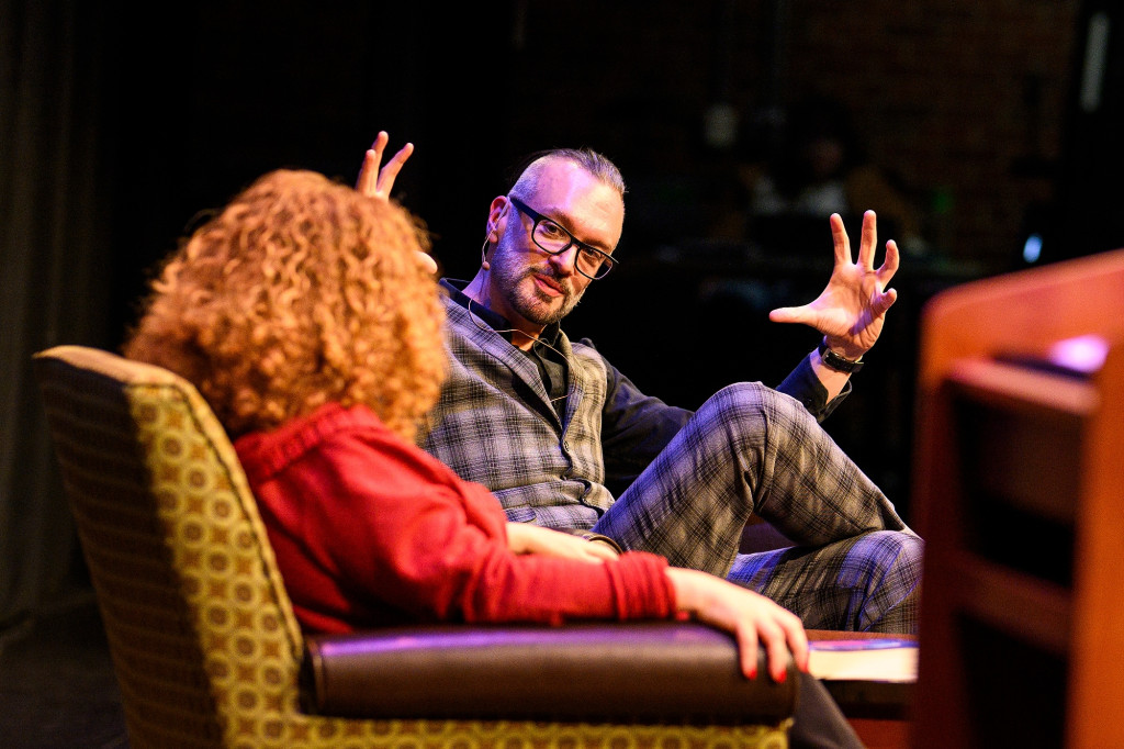 Two people sit on stage talking.