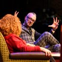 Two people sit on stage talking.