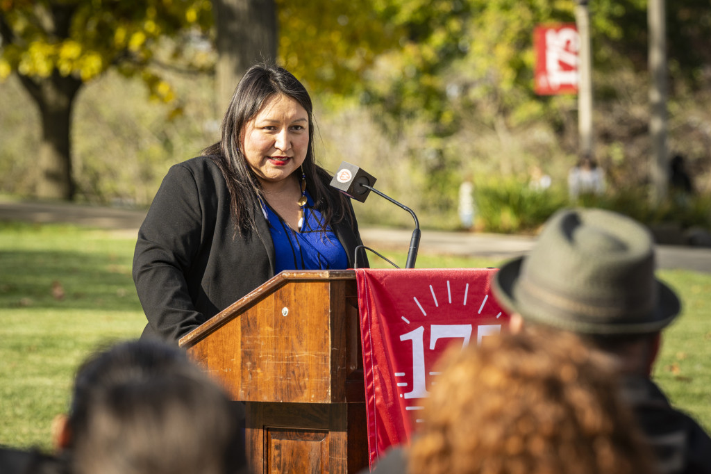 A woman smiles as she speaks to the audience from the podium.