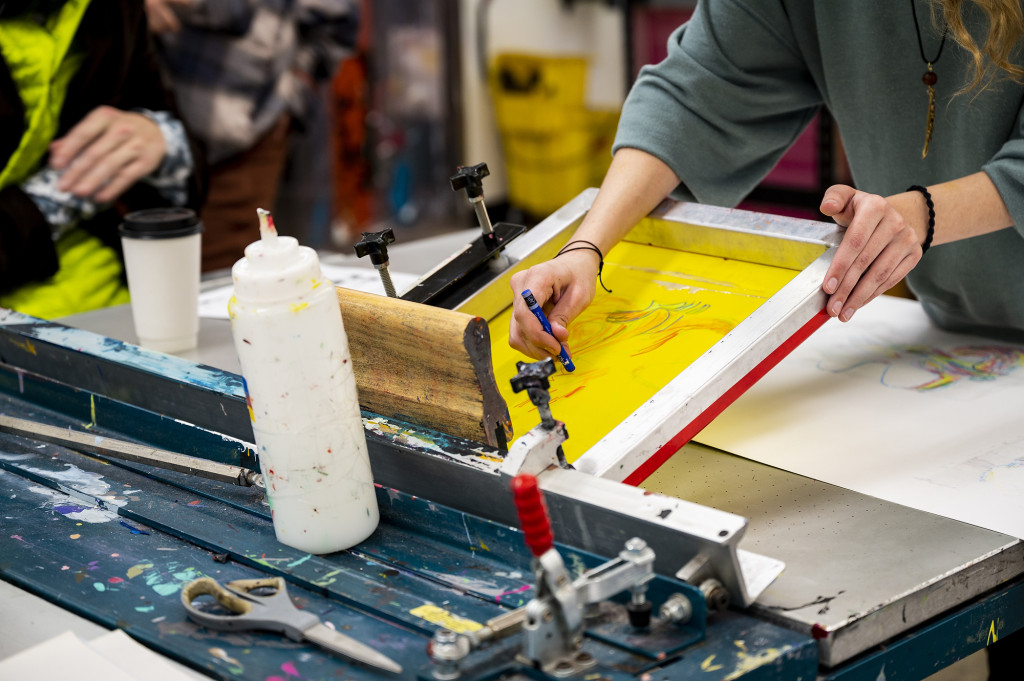 A person draws on a screen printing machine.