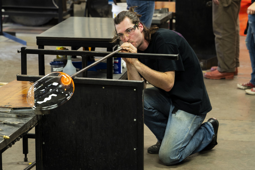 A man works with a glass instrument.