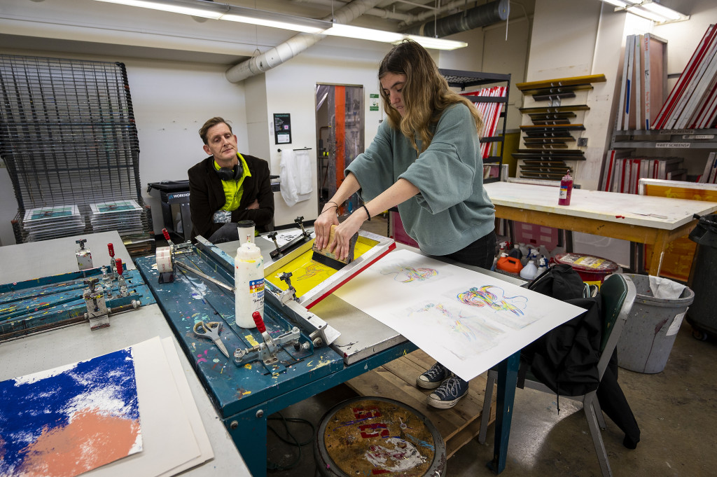 A person operates a screen-printing machine.