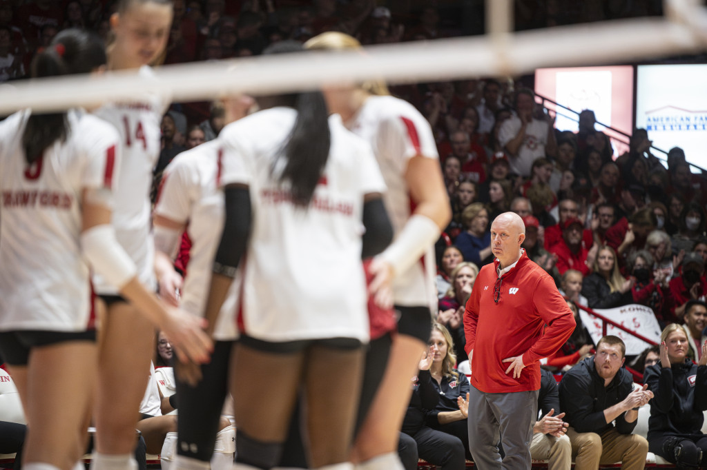 A man watches players play volleyball.