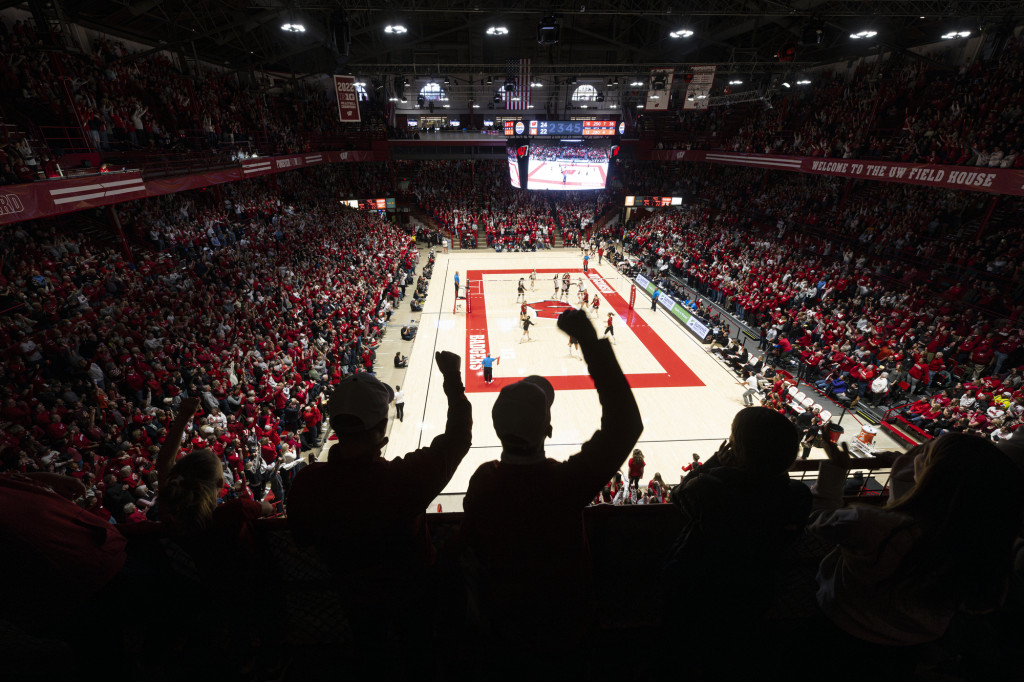 Cheering fans are silhouetted in the foreground, with the court in the background.