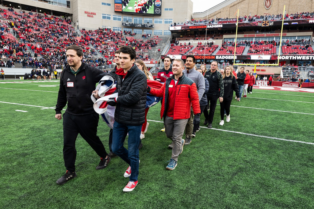 People carry a flag onto a football field.