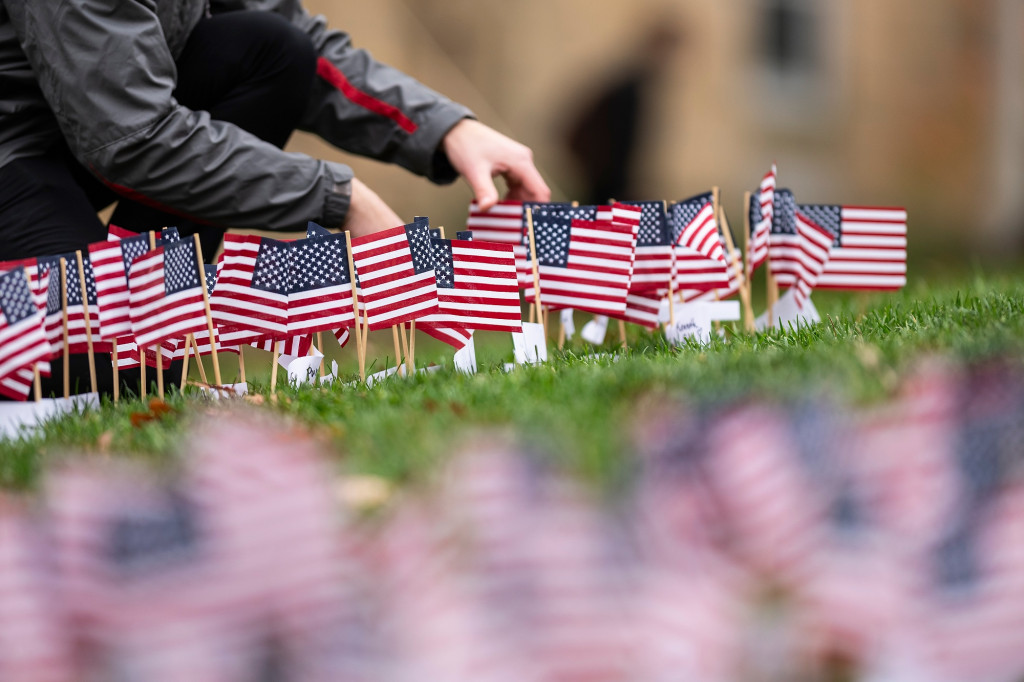 A person plants a flag in the grass.