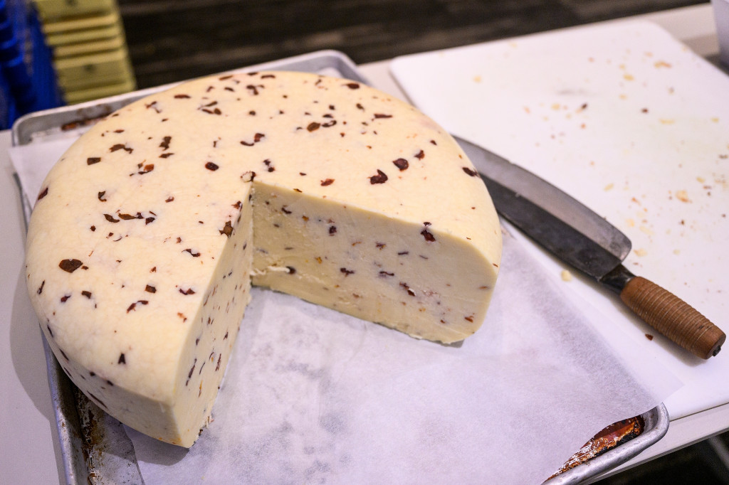 A wheel of yellow cheese with a big slice out of it.