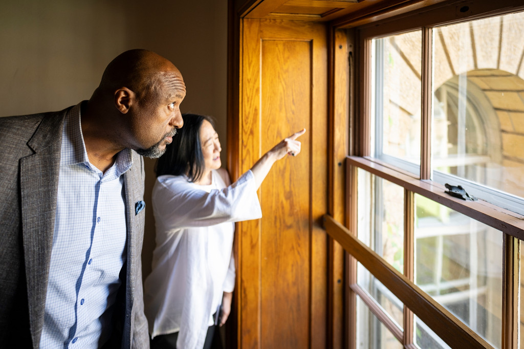 Charles Isbell looks up as he looks out a large, wood-cased window in Bascom Hall. Just behind him, Eden Inoway-Ronnie points out the window toward something out of frame.