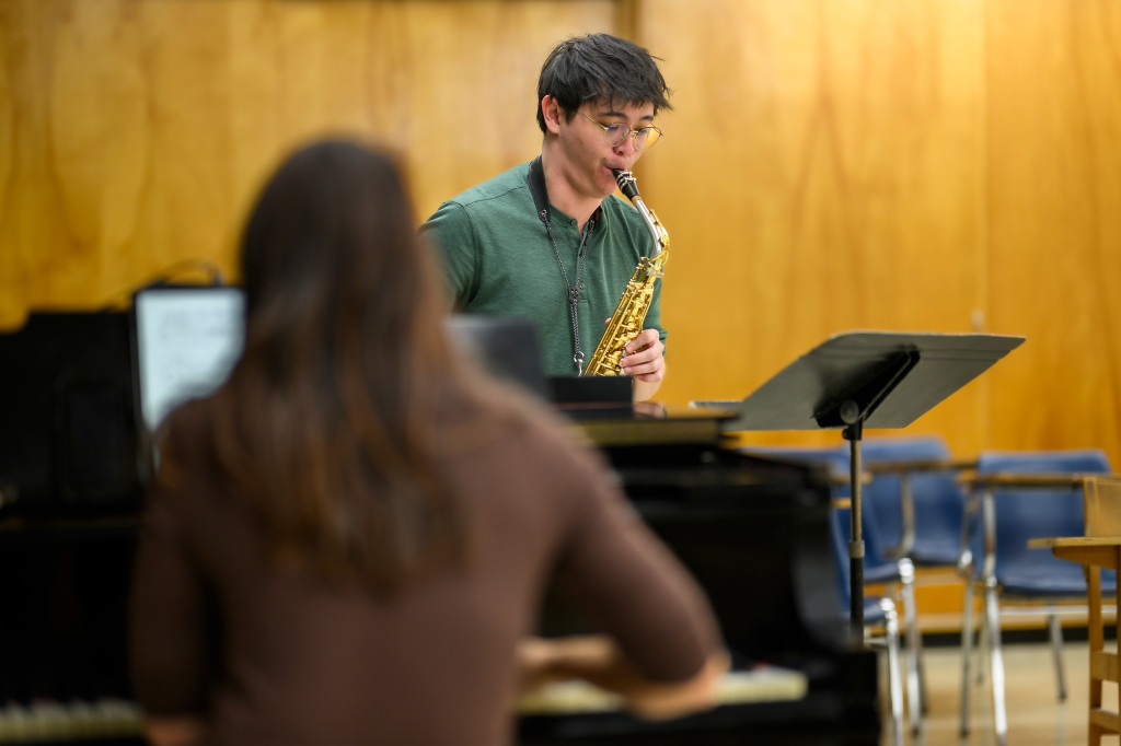 A person plays piano and another plays saxophone.