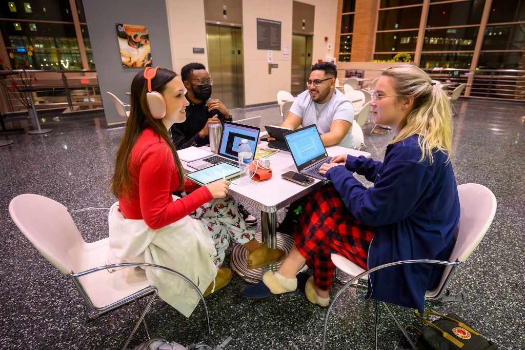 People crowd around a table, studying.