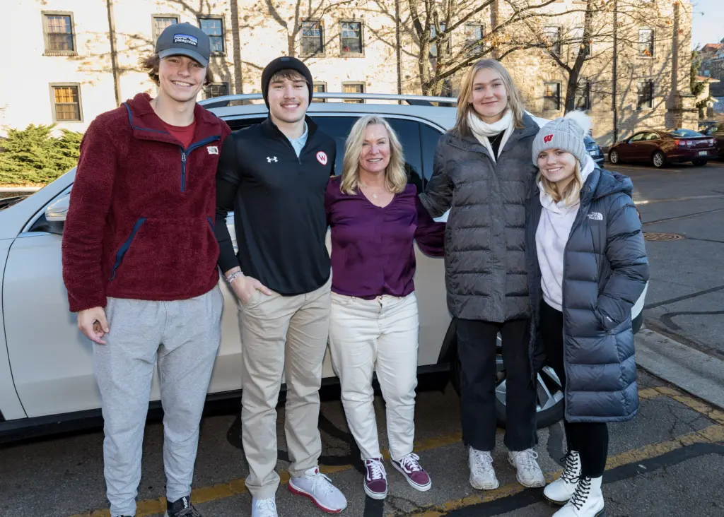 Five people stand arm in arm.