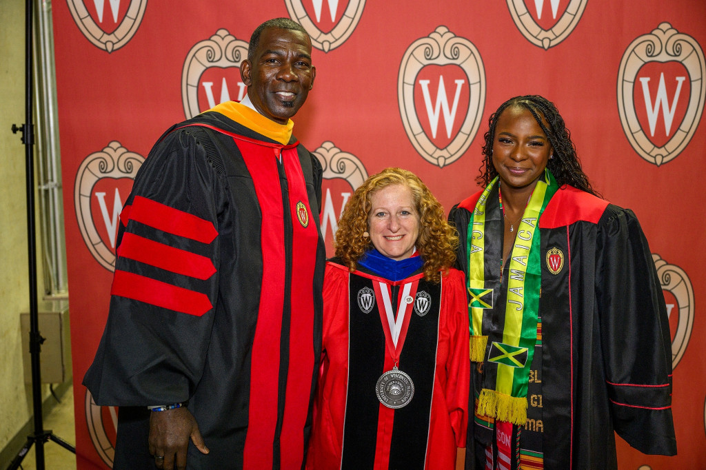 Three people pose for a photo, arm in arm, smiling.