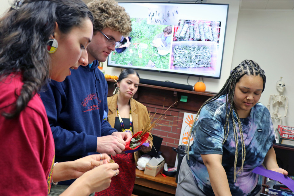 A group of students gather around a table learning about herbs used for medicine.