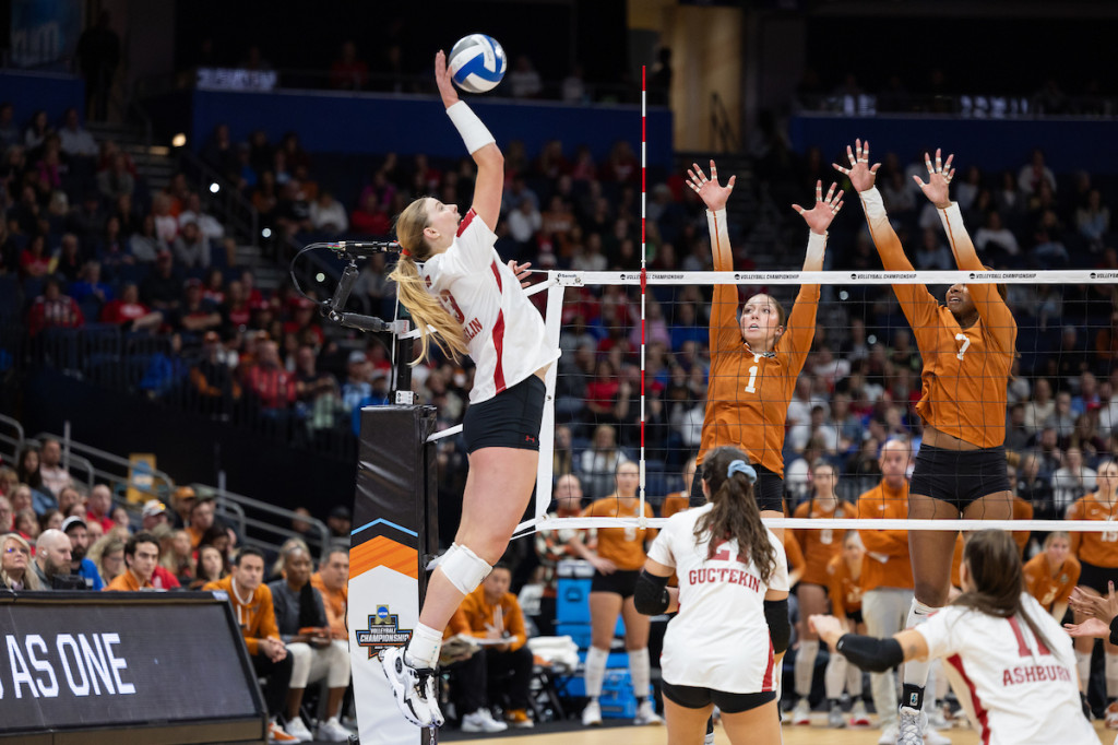 A woman smashes the ball as she jumps high.