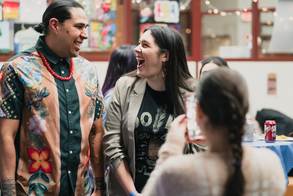 A young woman laughs at a joke from the man standing next to her.