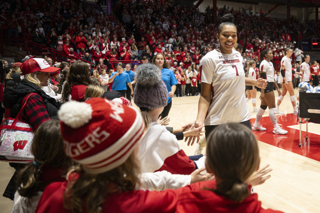 A volleyball player gives a high five to a young fan.