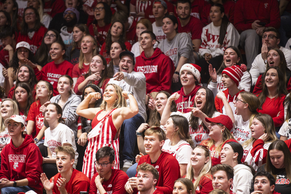 A woman in the volleyball crowd raises her arms.