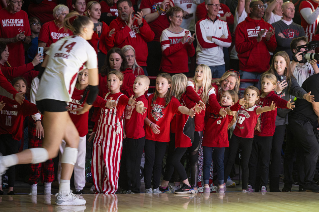 A woman runs by a row of kids holding up their hands to high-five.