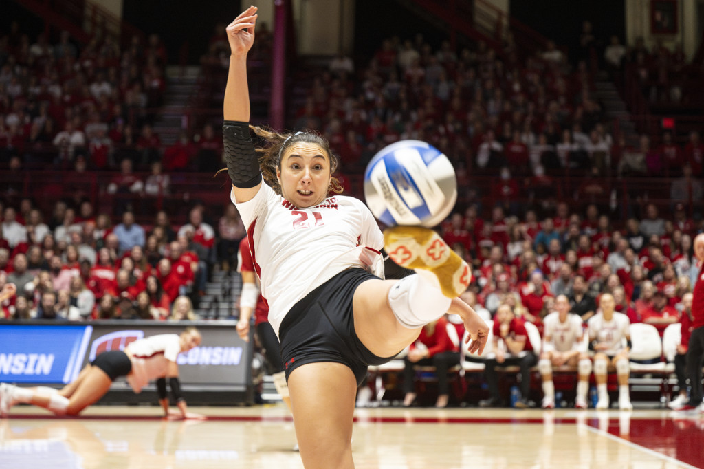 A woman kicks a volleyball.