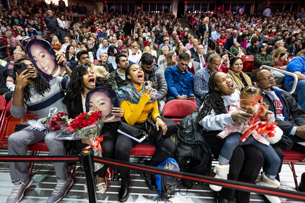 Family members sitting in the stands cheer and smile.