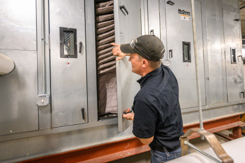 A man checks air filters in machinery.