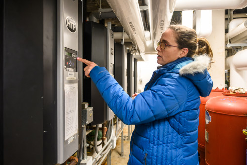 A woman looks over dials on a furnace.