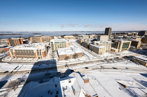 A panoramic shot of a snow-colored campus, with lake in background.