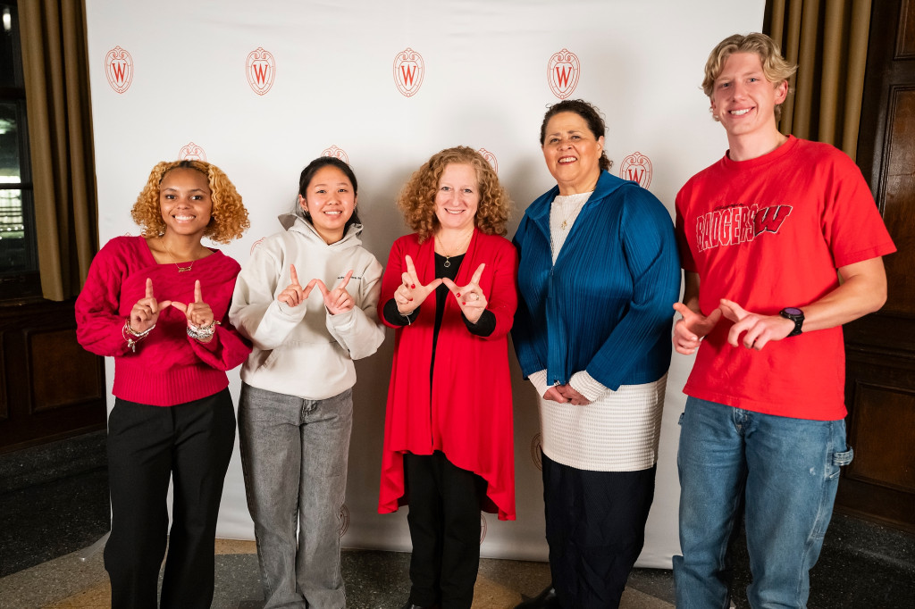 Five people pose for the camera and hold up their hands in W formation.