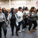 Students and staff stand in a line dancing.