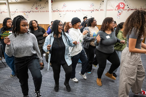 Students and staff stand in a line dancing.