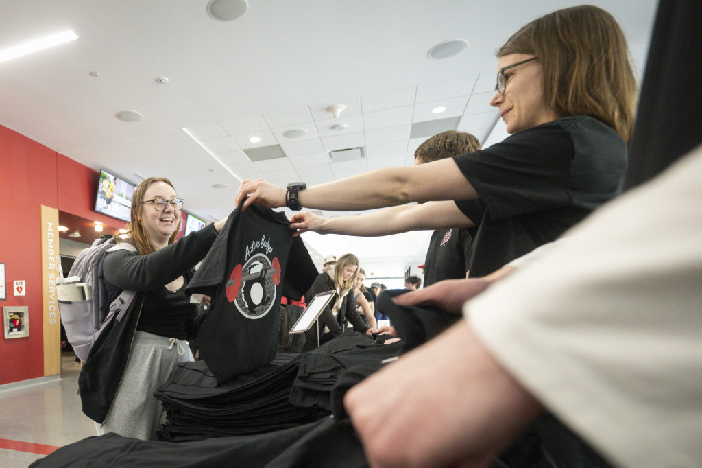 At a long table, students line up to receive free T-shirts as part of Active Badger Day.