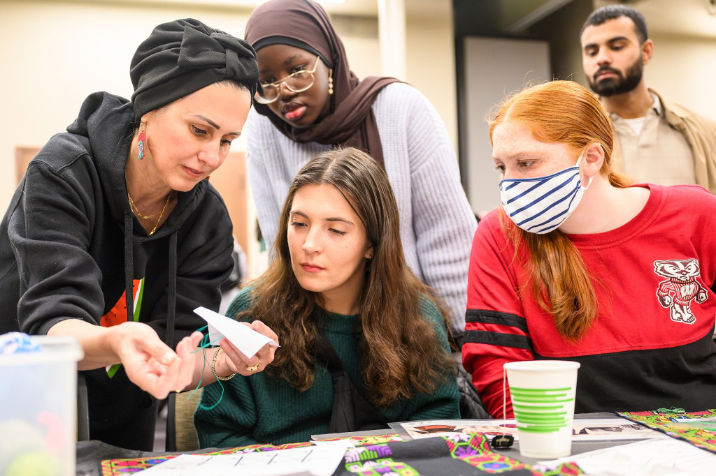 Several people at a table work on an embroidery project.