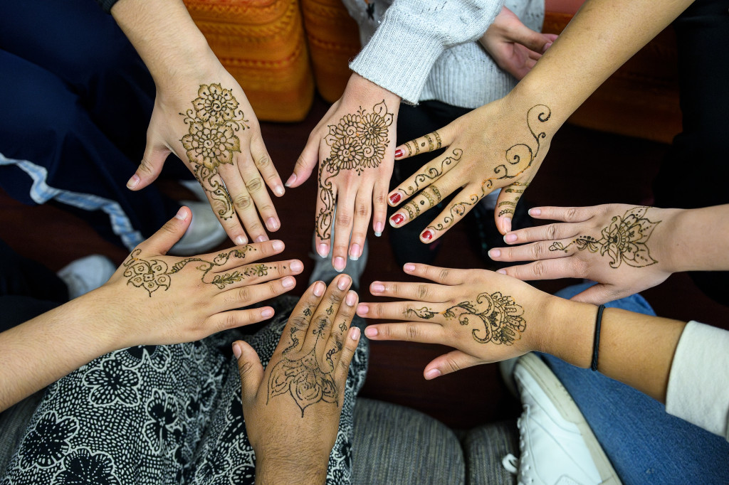 Seven hands painted intricately are displayed in a circle.