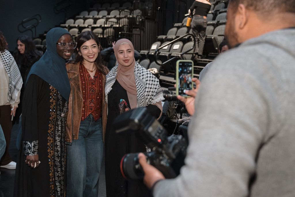 A man uses a camera to take a picture of three people.