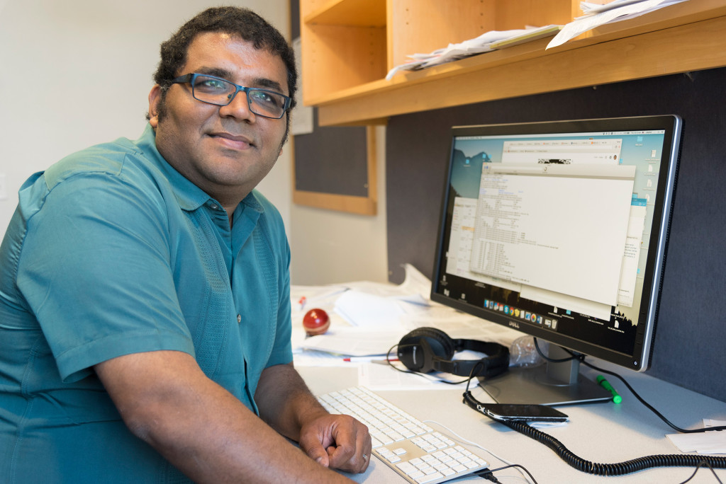 A photo of Vatsan Raman sitting at a computer desk.