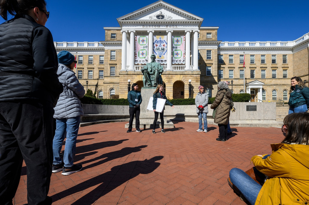 A group of people gather around two speakers in front of Bascom Hall.