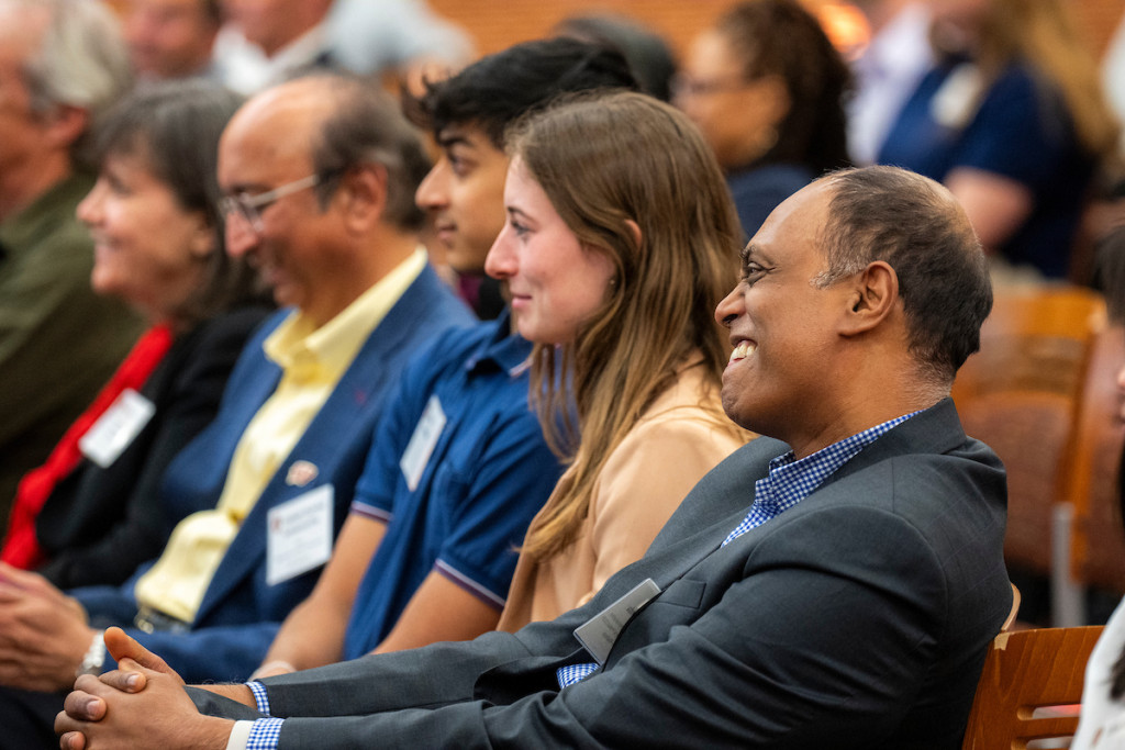 People sitting in an audience laugh and smile.