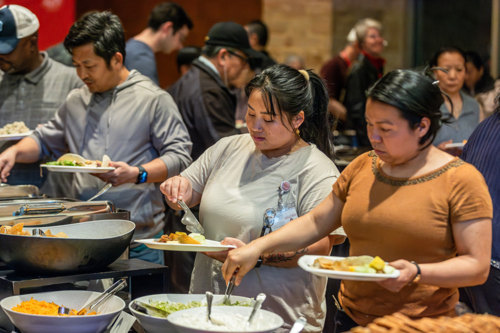 People ladle food onto their plates.